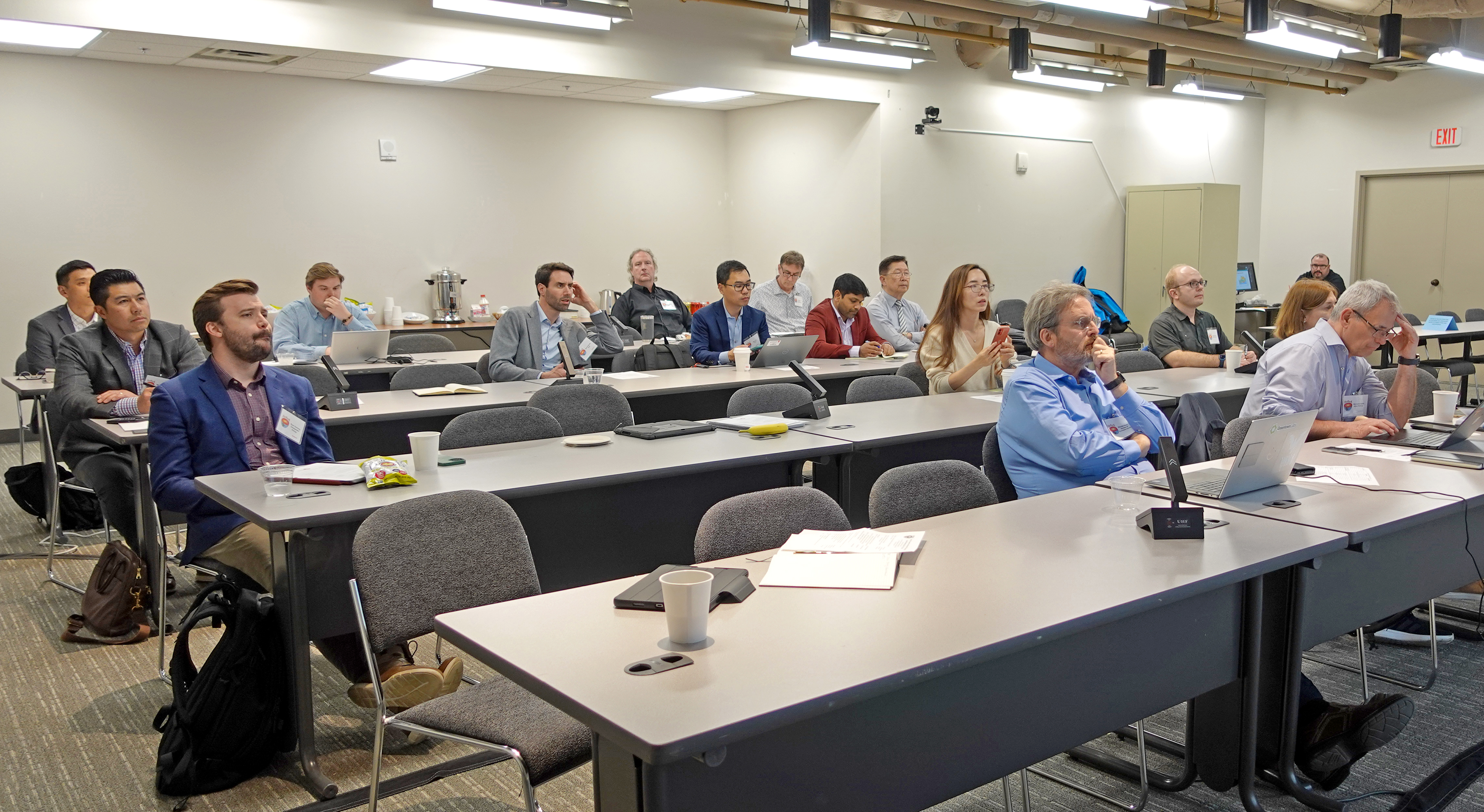 A diverse group of representatives from oil and gas organizations sit in a lecturing hall listening to a presentation by one of the HotRock researchers (out of frame).