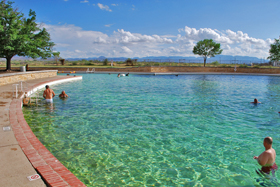 The clear waters of San Simeon Spring flow into a public swimming and diving pool in the park; the Davis Mountains behind.